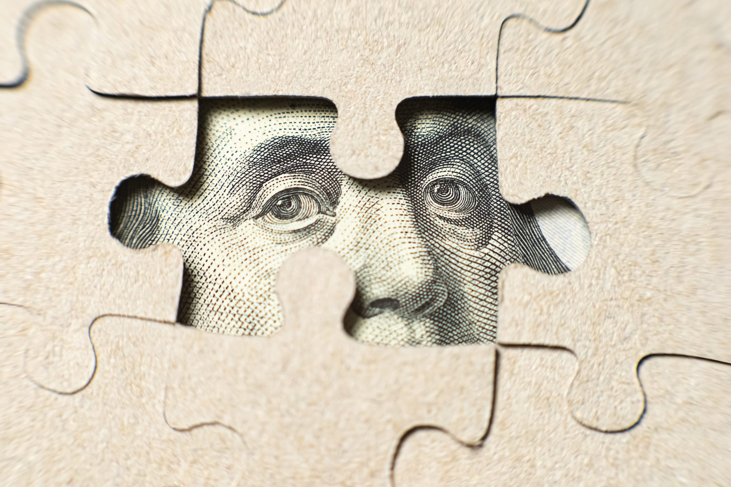 Benjamin Franklin on a US bill looking through an empty spot on a puzzle where a piece is missing